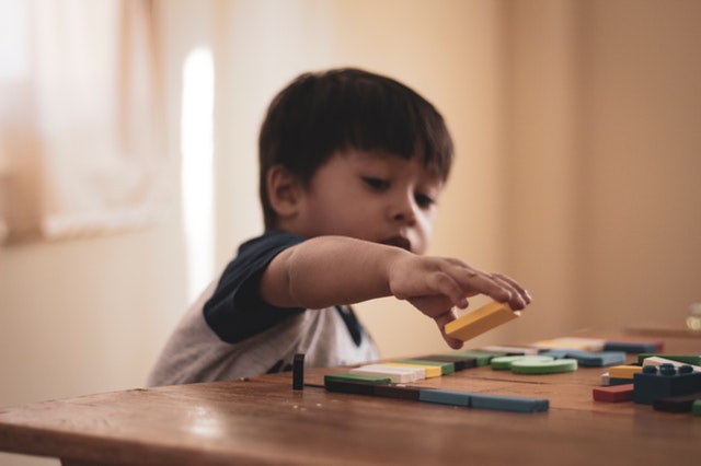 menino brincando com blocos coloridos em cima de uma mesa